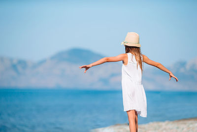 Midsection of woman with arms raised against sky