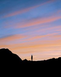 Silhouette man standing on mountain against sky during sunset