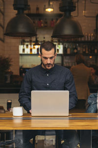 Man using laptop while sitting at table in cafe