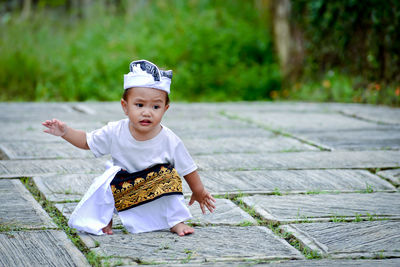 Full length of cute boy wearing costume crouching outdoors