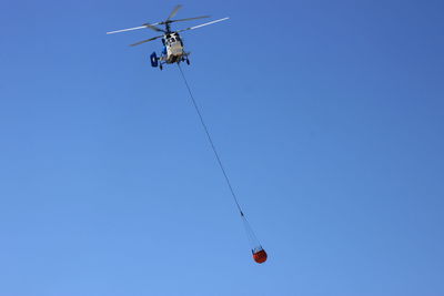 Low angle view of helicopter against clear blue sky