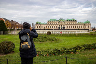 Young girl with camera is taking a photo at schloss belvedere in vienna. 