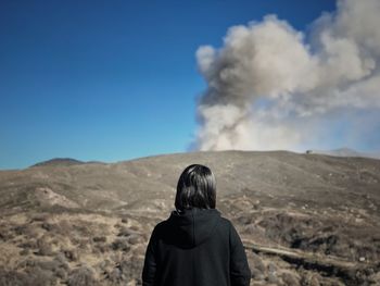 Rear view of man looking at mountain against sky