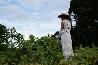 Woman standing by plants against sky