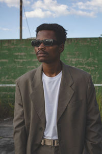 Young man wearing sunglasses while standing against trees