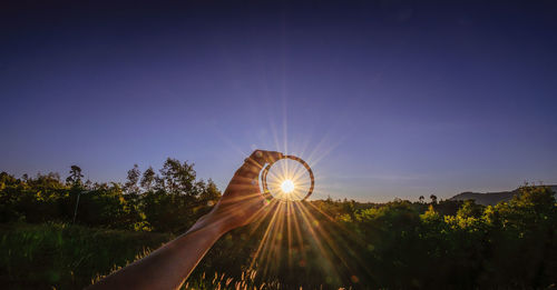 Sunlight streaming through glass held by person against sky