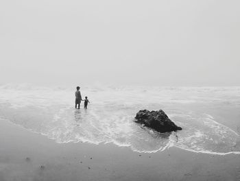 Rear view of father and son at the beach on a foggy day