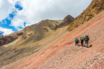 Rear view of people walking on mountain against sky