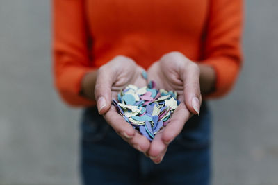 Multi colored confetti in hands of young woman