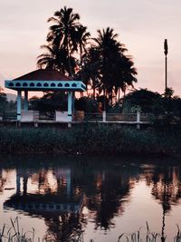 Palm trees by swimming pool against sky during sunset