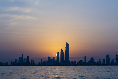 Scenic view of sea and buildings against sky during sunset