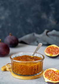 Fig jam in a glass jar with fresh fruits on grey concrete background. vertical banner