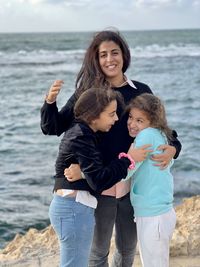 Portrait of mother with two young girls daughters standing near the beach sea