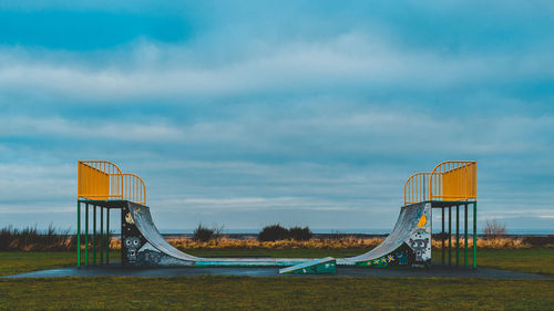 Skateboard ramp at park against cloudy sky