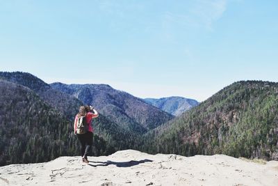 Rear view of man on snowcapped mountain against sky