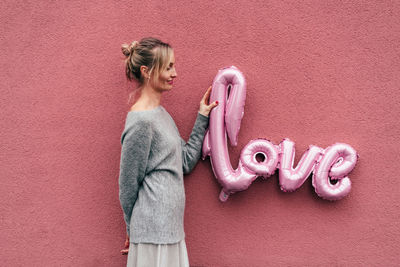 Midsection of woman standing against pink wall