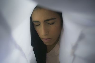 Close-up of woman with eyes closed covered by textile