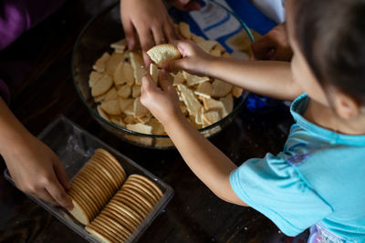 Hands making malaysian triple chocolate dessert.  crushing the cookies into tiny pieces.