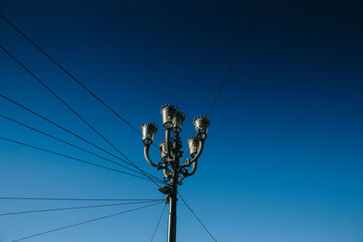 Low angle view of electricity pylon against blue sky