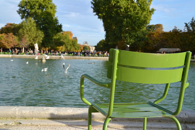 Empty green chair by pond at tuileries garden