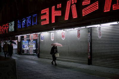 Man walking on illuminated street at night