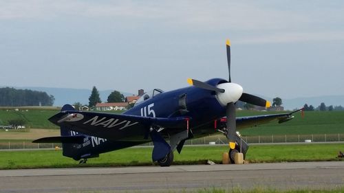 Airplane at airport runway against sky