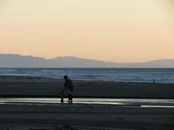 Full length of man walking on beach against clear sky