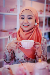 Portrait of a smiling young woman drinking coffee