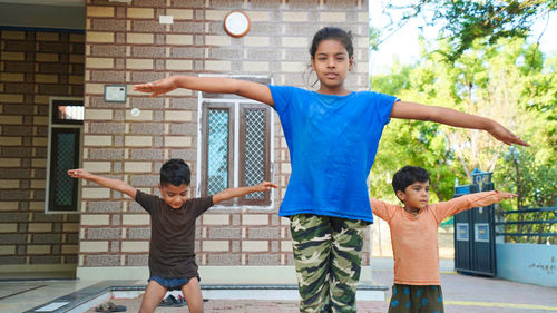 Three indian little kids doing meditate yoga asana on roll mat at home.