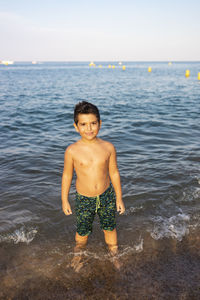 Cute boy on the shore of the beach into the sea