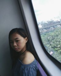 Young woman standing by window in cable car