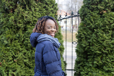 Portrait of smiling woman standing against plants