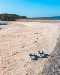 View of shoes on beach against blue sky