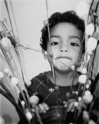 Close-up portrait of boy standing behind decoration by wall