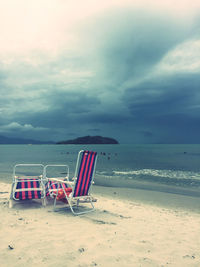 Chairs on beach against sky