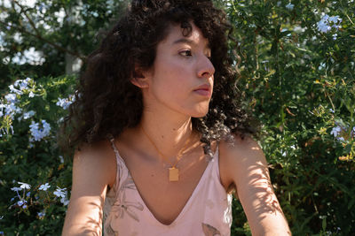 Portrait of beautiful young woman standing against plants