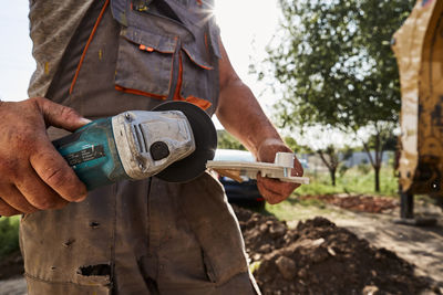 Low section of man working at construction site with the sun behind