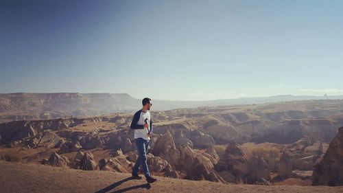 Full length of hiker walking on mountain against sky