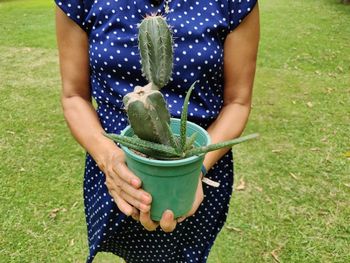 Midsection of woman holding plant on field