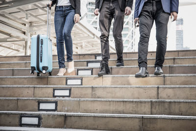 Low section of colleagues walking on steps