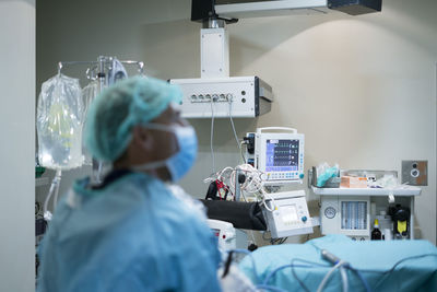 Blurred man in surgeon uniform looking away while conducting surgery in modern operating theater