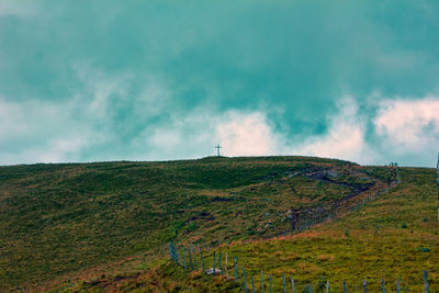 Scenic view of grassy field against cloudy sky