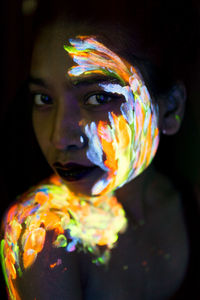 Close-up portrait of young woman with paint on face and shoulder