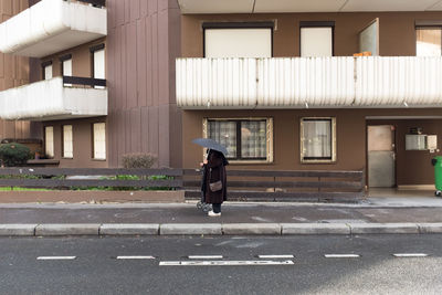 Full length of woman walking on street by building