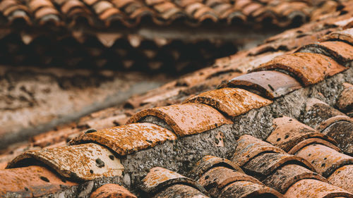 Overlapping rows of yellow and orange ceramic roofing tiles covering residential building roof.