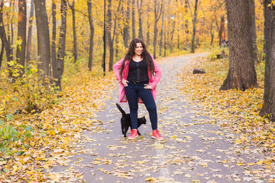 Full length of young woman with autumn leaves in forest