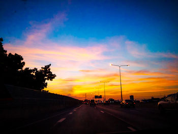 Cars on road against sky during sunset