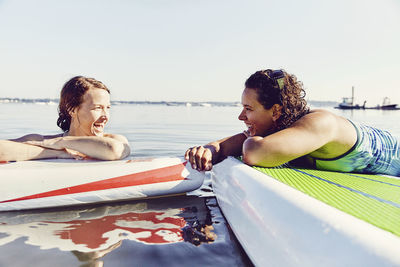 Two young female friends on standup paddle board in casco bay, maine