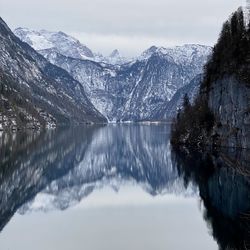 Scenic view of lake by snowcapped mountains against sky