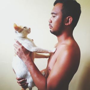 Side view of young man with dog against white background